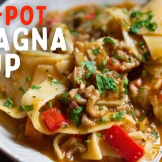 a bowl of lasagna soup sits garnished with fresh basil and parsley