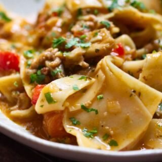 a bowl of lasagna soup sits garnished with fresh basil and parsley