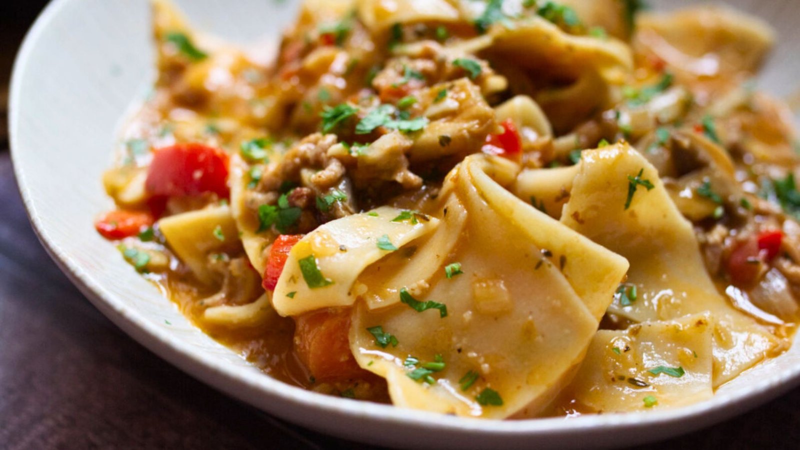 a bowl of lasagna soup sits garnished with fresh basil and parsley