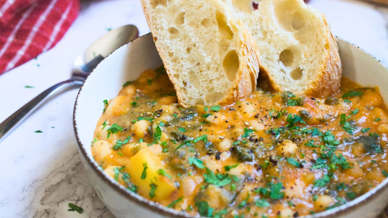 a bowl of white bean soup with some crusty bread slices