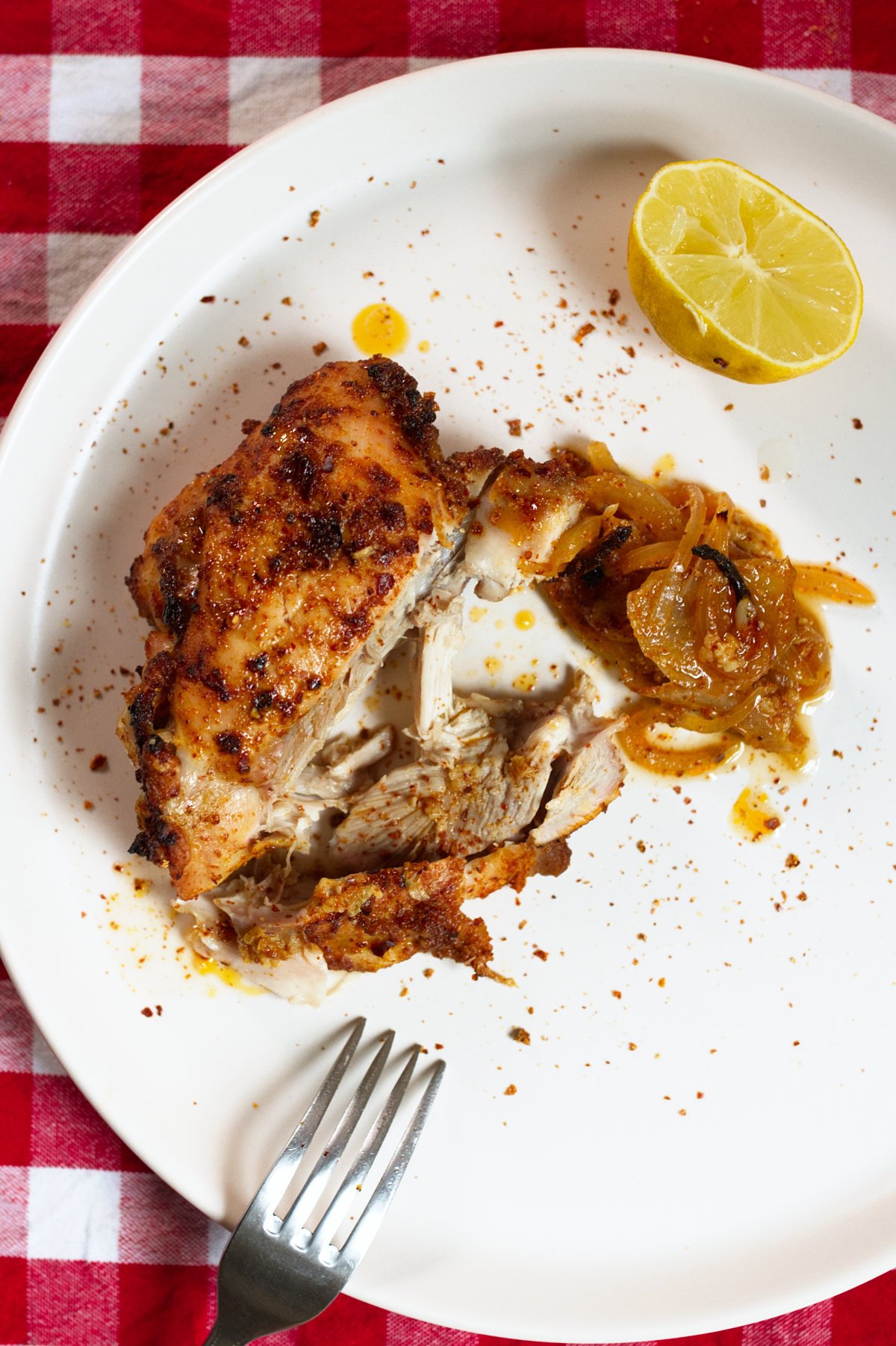 A plate with a spicy Mediterranean chicken thigh served with some lemon