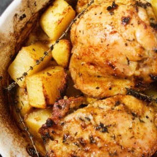 A large pan of chicken and potatoes with lemon and thyme