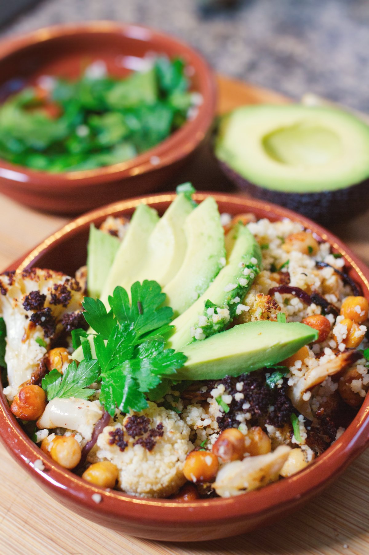 Spicy Roast Cauliflower and Chickpeas-lut-v2 - happymediterranean.com A bowl of sicy roasted cauliflower and chickpeas beside some sliced avocado