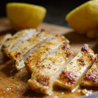 A marinated chicken breast a sliced on a chopping board