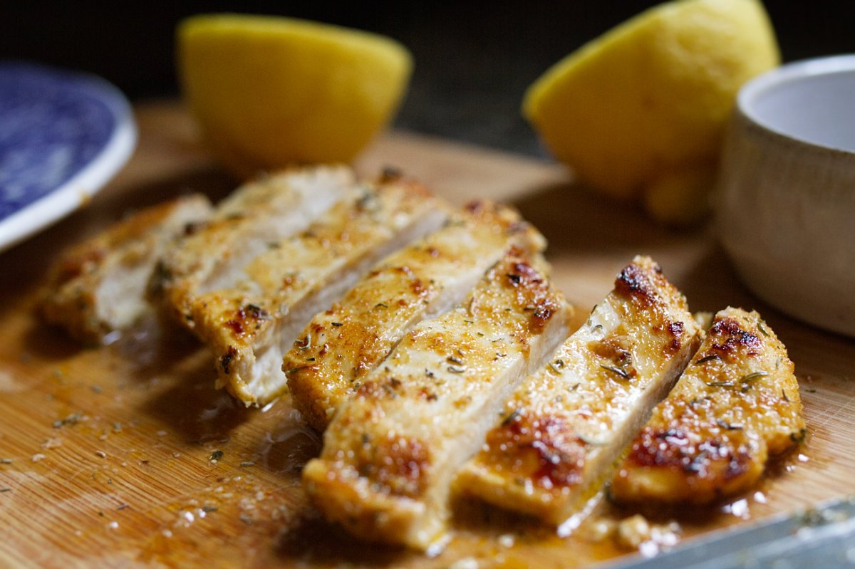 A marinated chicken breast a sliced on a chopping board