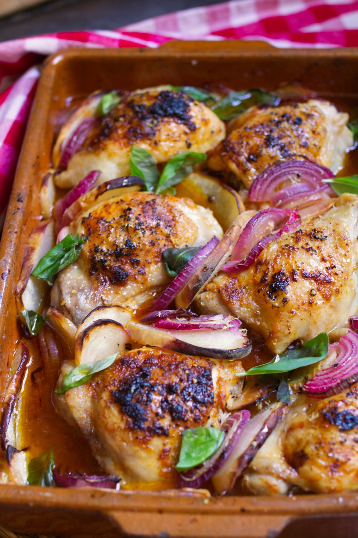 A large pan of Summer chicken with peaches garnished with some fresh basil