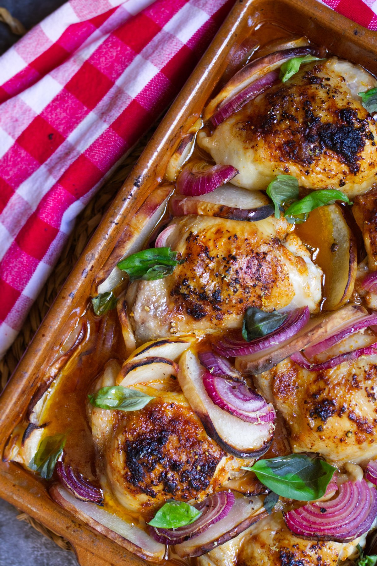 A large pan of Summer chicken with peaches garnished with some fresh basil