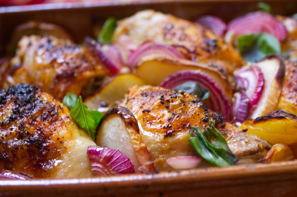 A large pan of Summer chicken with peaches garnished with some fresh basil