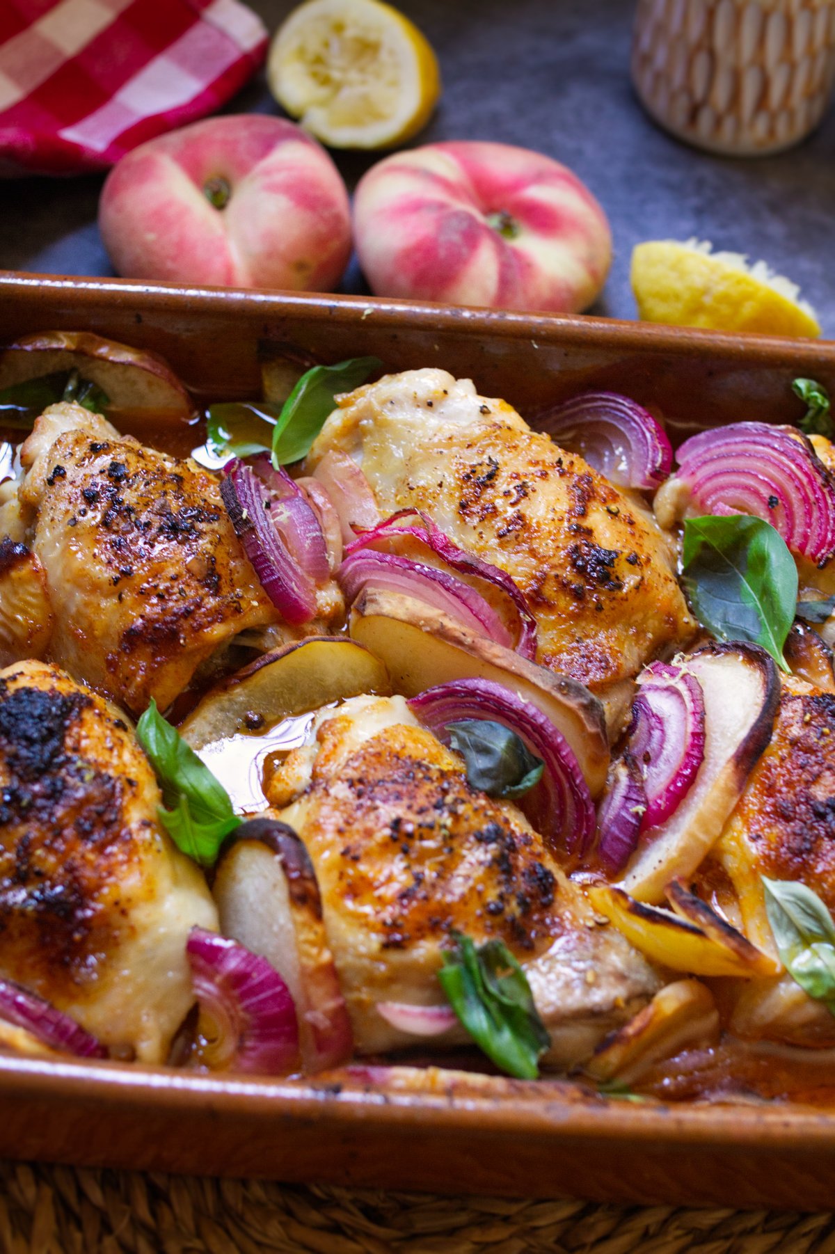 A large pan of Summer chicken with peaches garnished with some fresh basil