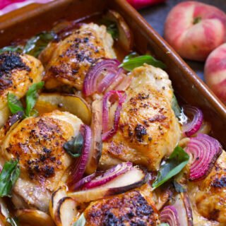 A large pan of Summer chicken with peaches garnished with some fresh basil