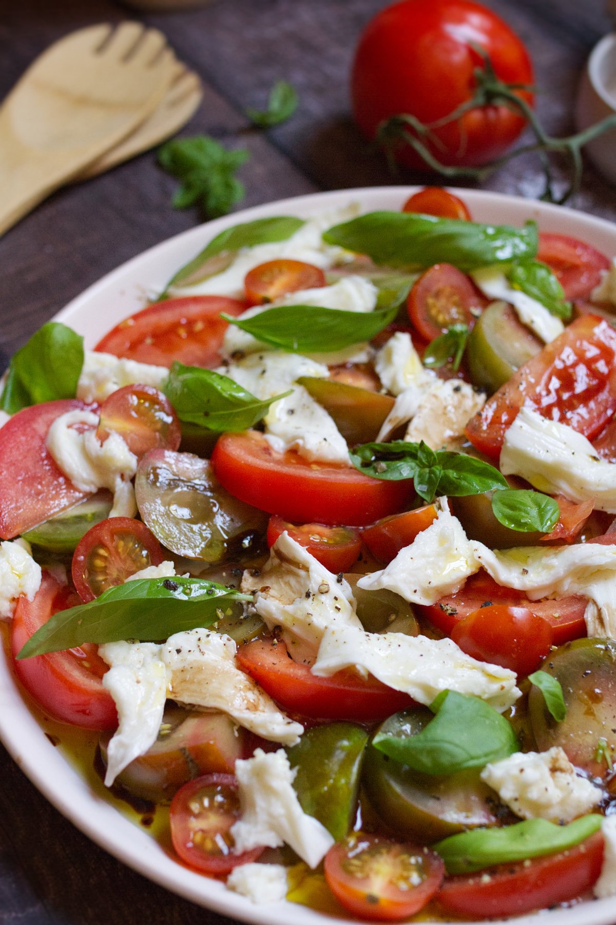 tomato mozzarella salad-v18 - happymediterranean.com A large platter of tomato mozzarella salad garnished with fresh basil leaves