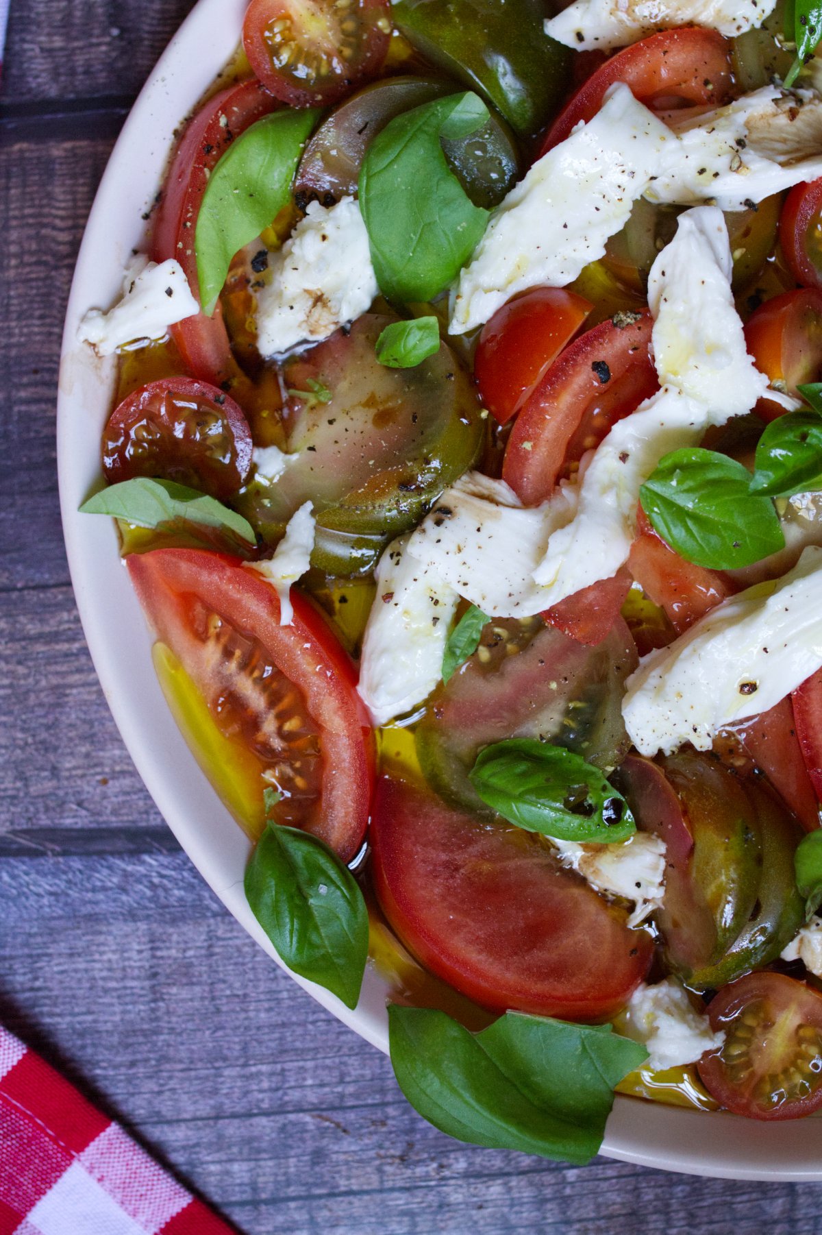 tomato mozzarella salad-v33 - happymediterranean.com A large platter of tomato mozzarella salad garnished with fresh basil leaves