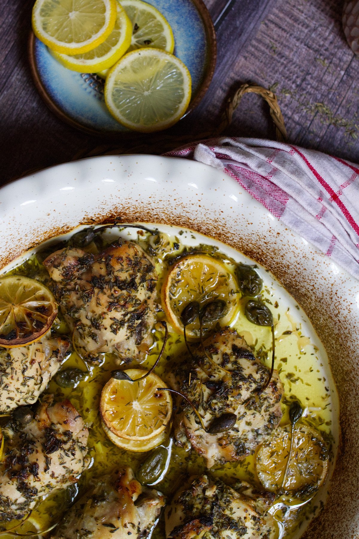 A large dish of Greek lemon and herb chicken thighs sits waiting to be served