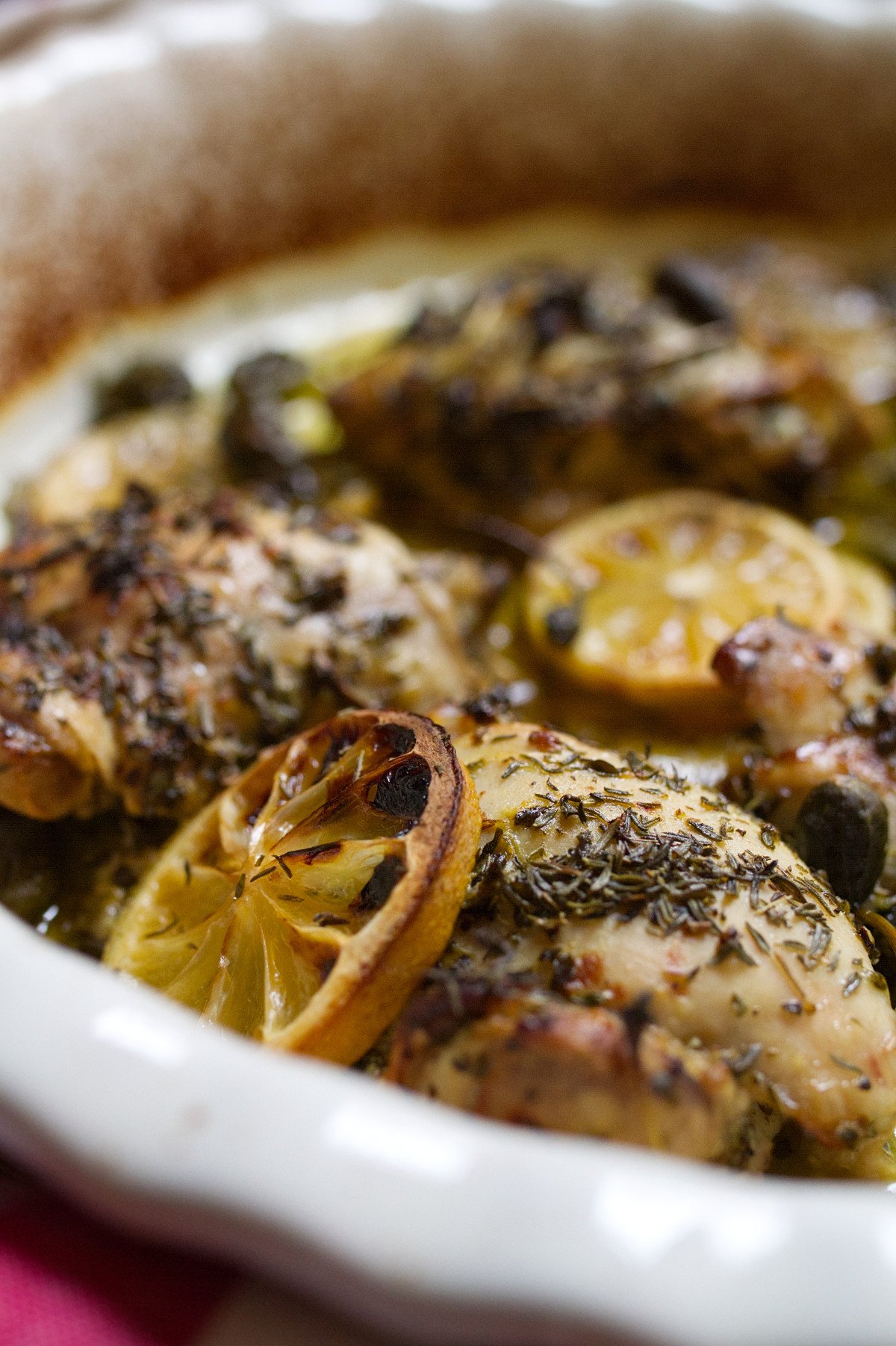 A large dish of Greek lemon and herb chicken thighs sits waiting to be served
