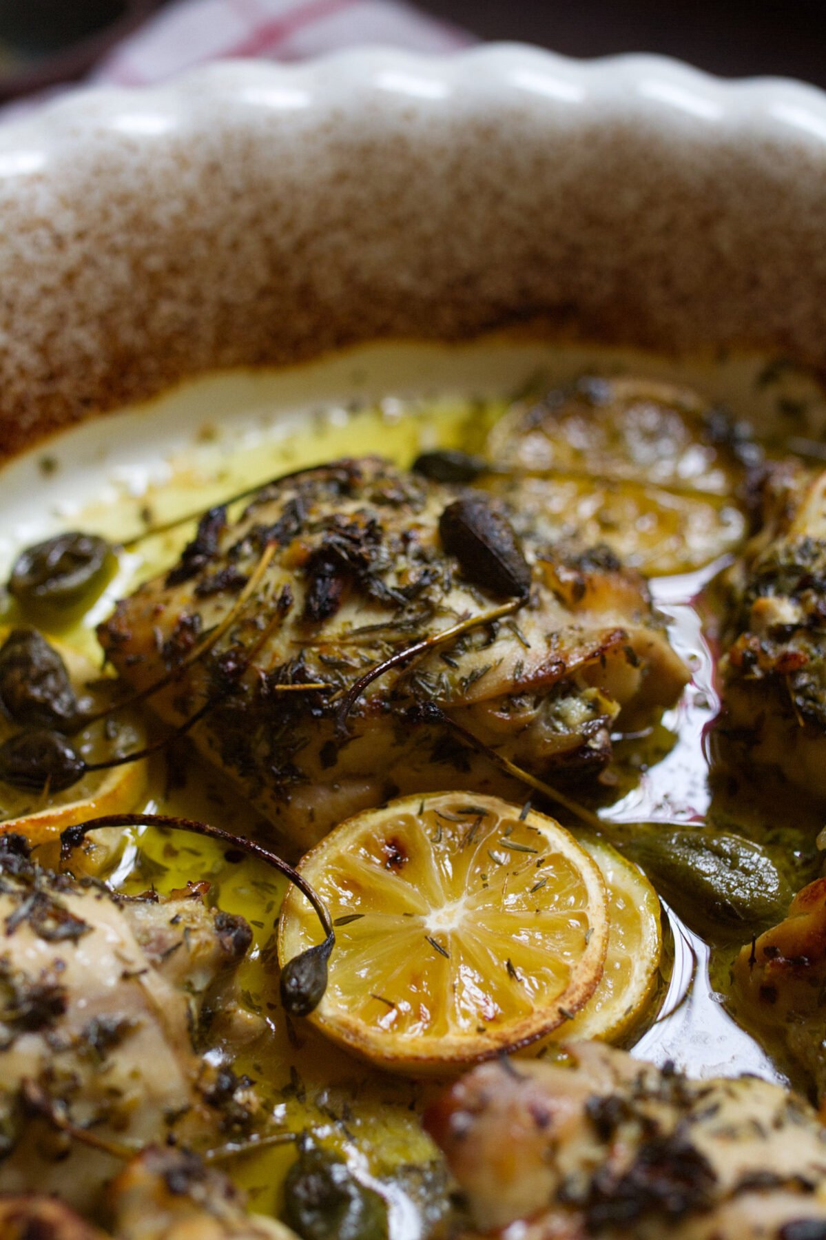 A large dish of Greek lemon and herb chicken thighs sits waiting to be served
