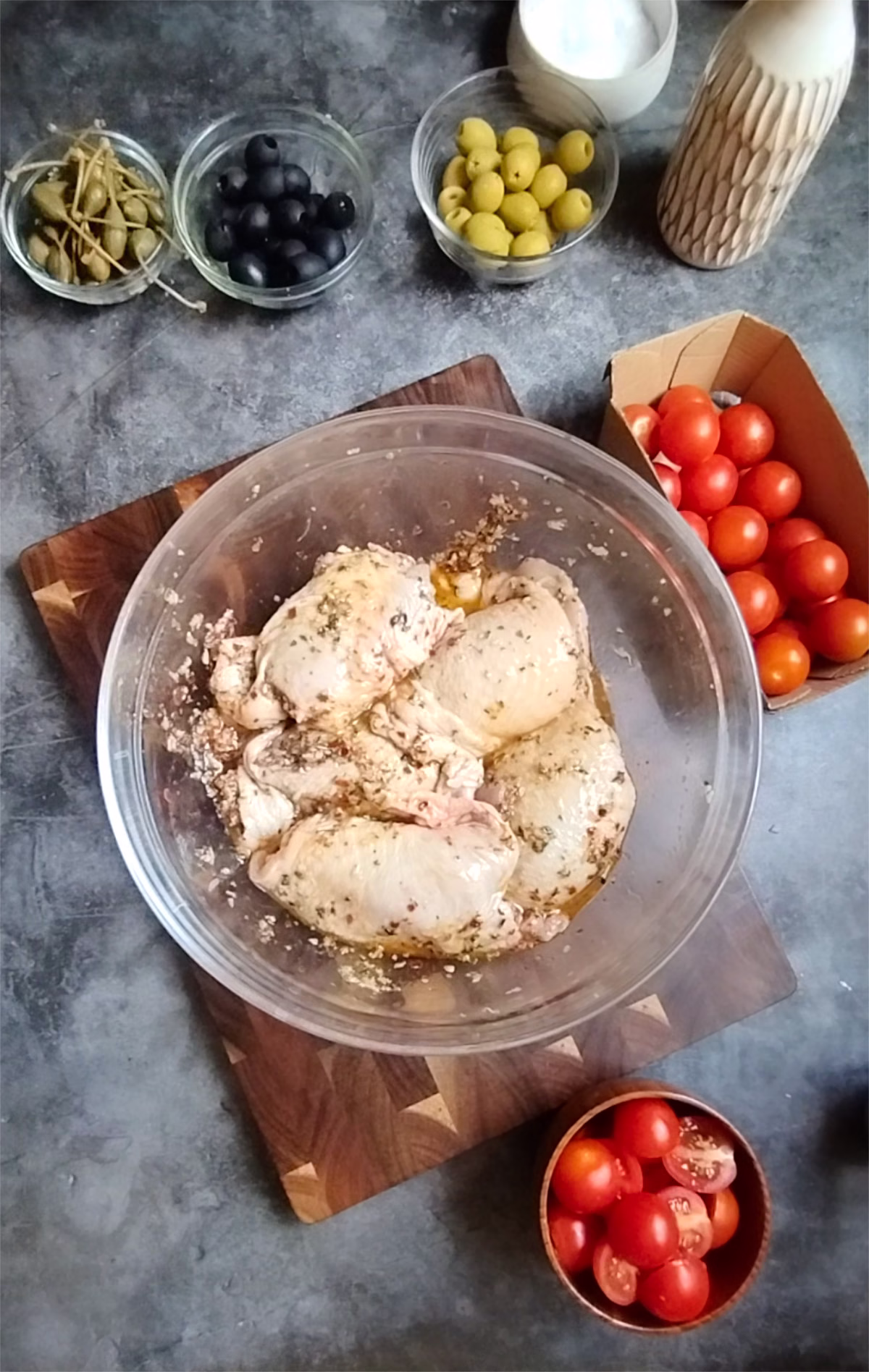 some marinated chicken beside some olives an capers
