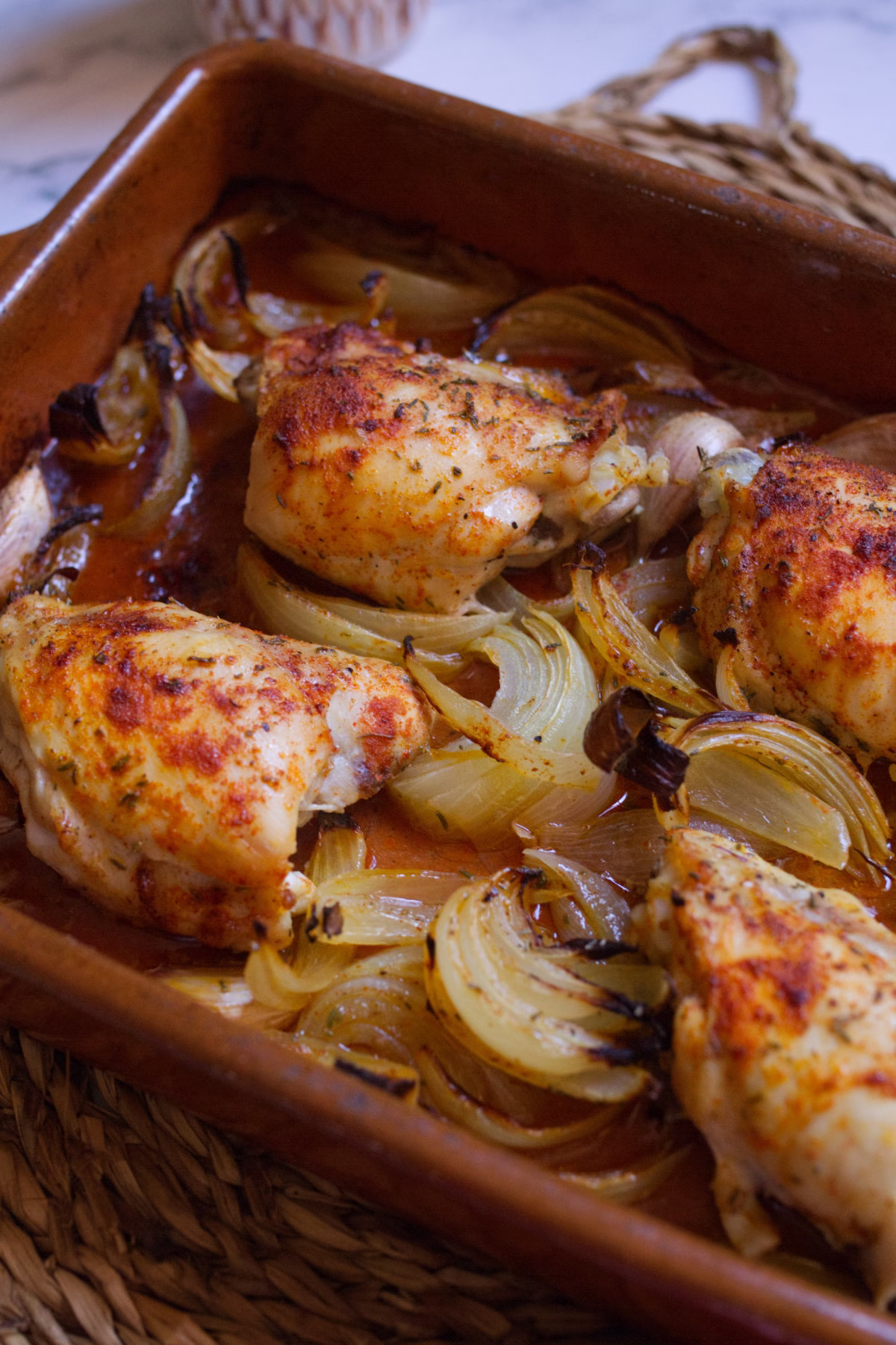 Mediterranean chicken thighs-v1 - happymediterranean.com a pan of chicken thighs with cooked onion and garlic