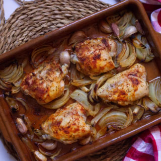 a pan of chicken thighs with cooked onion and garlic